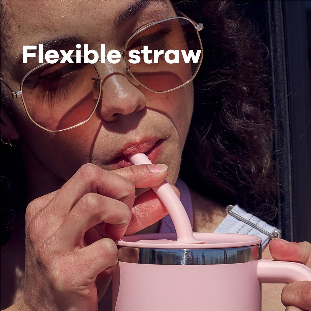 Close-up of a pink travel tumbler with flexible straw and lid while drinking.