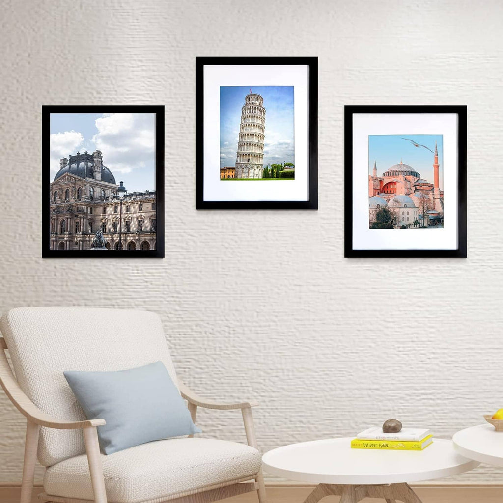 Three black picture frames with white mats displaying photos on a wall.