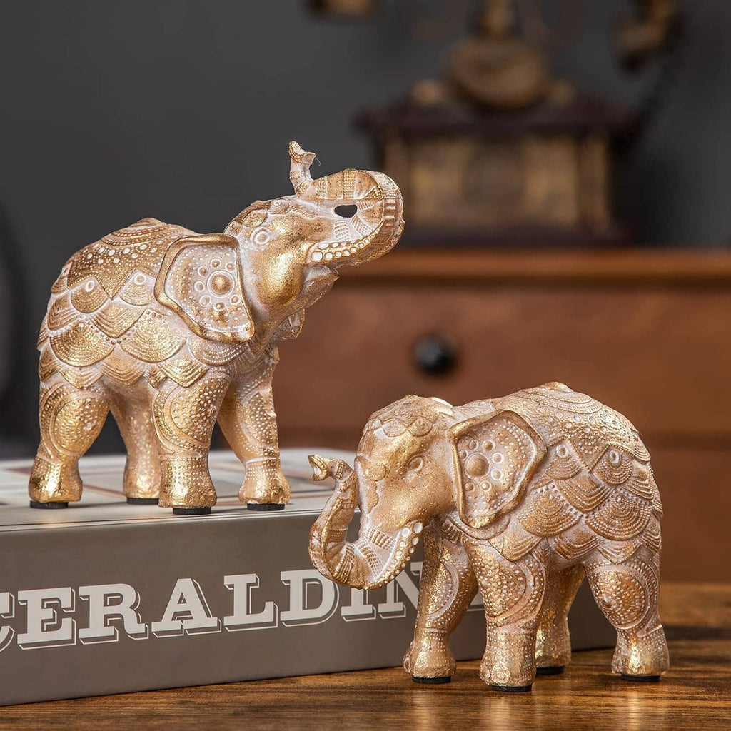 Two gold elephant statues figurines, trunk raised on one, ornate textured markings