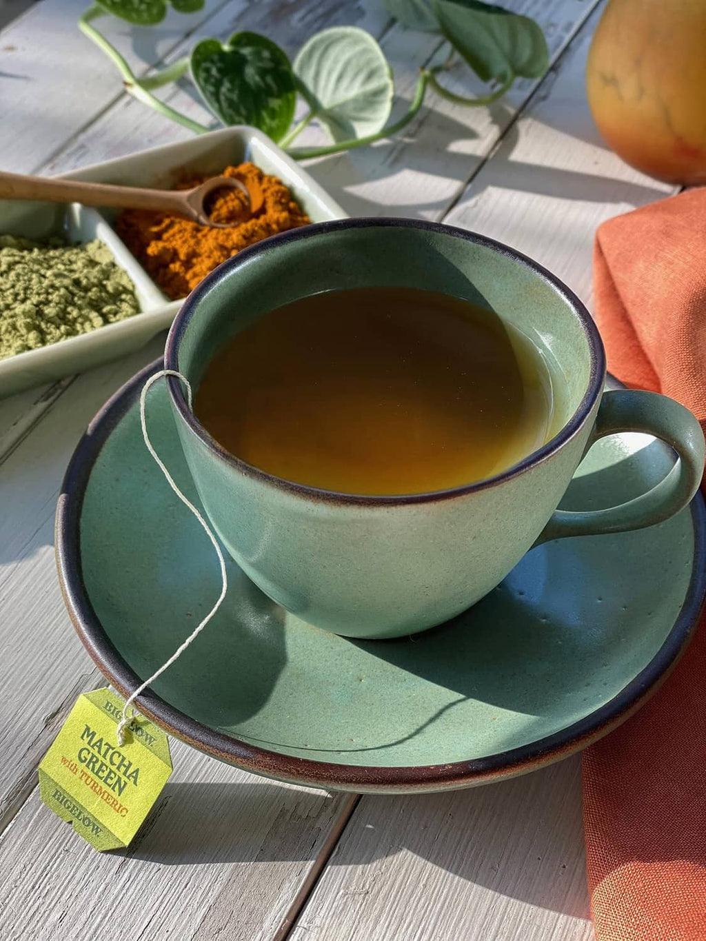 Caffeinated matcha green tea cup with saucer and turmeric root on a wooden table