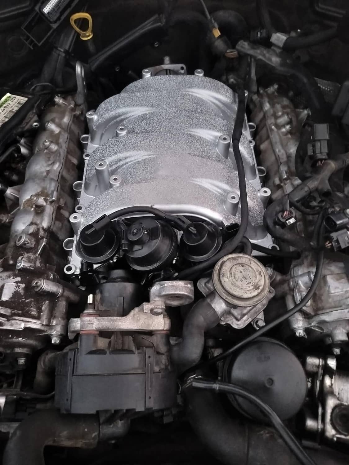 Engine bay close-up of installed silver intake manifold with black vacuum lines