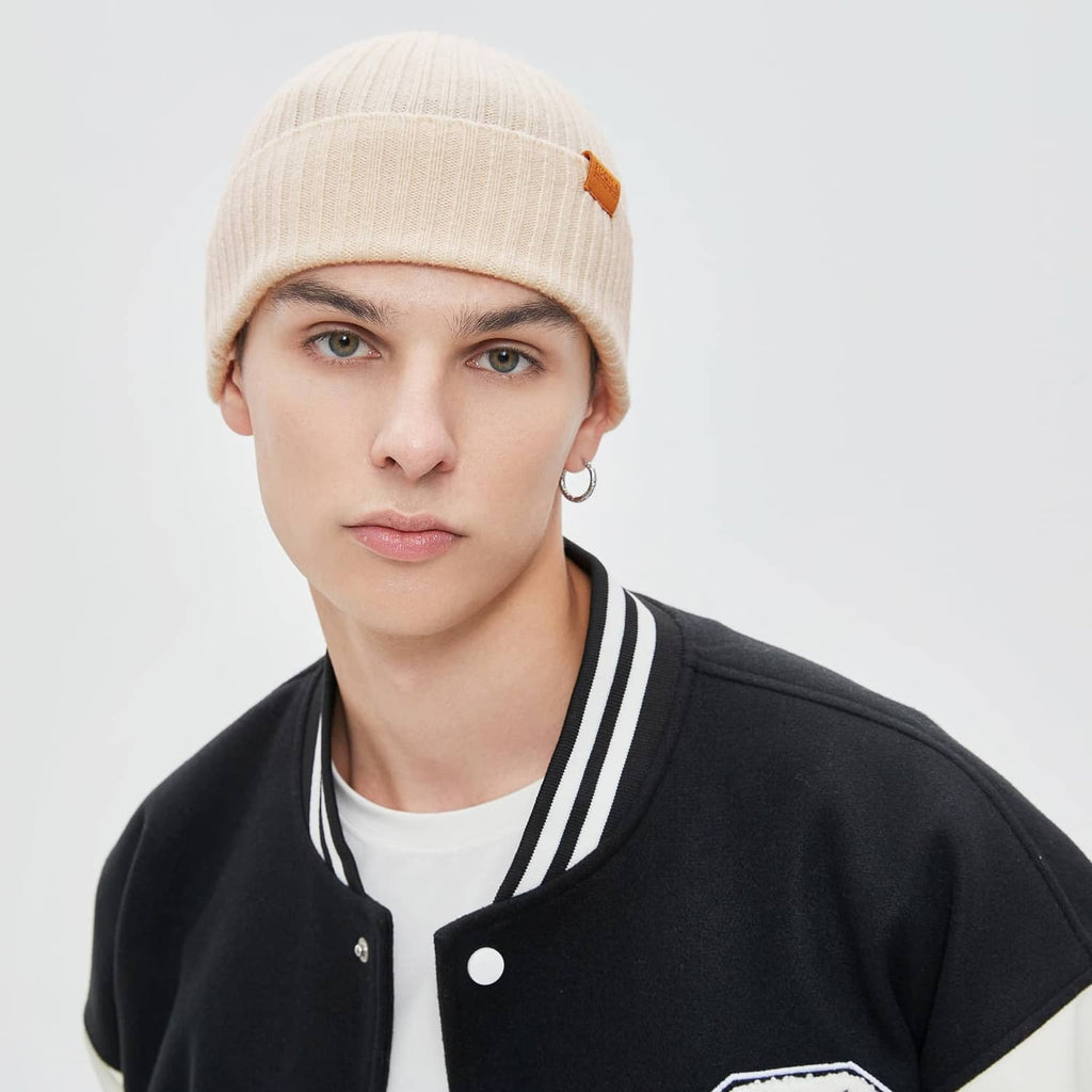 Beige knit beanie with folded cuff and leather logo patch, front view on model