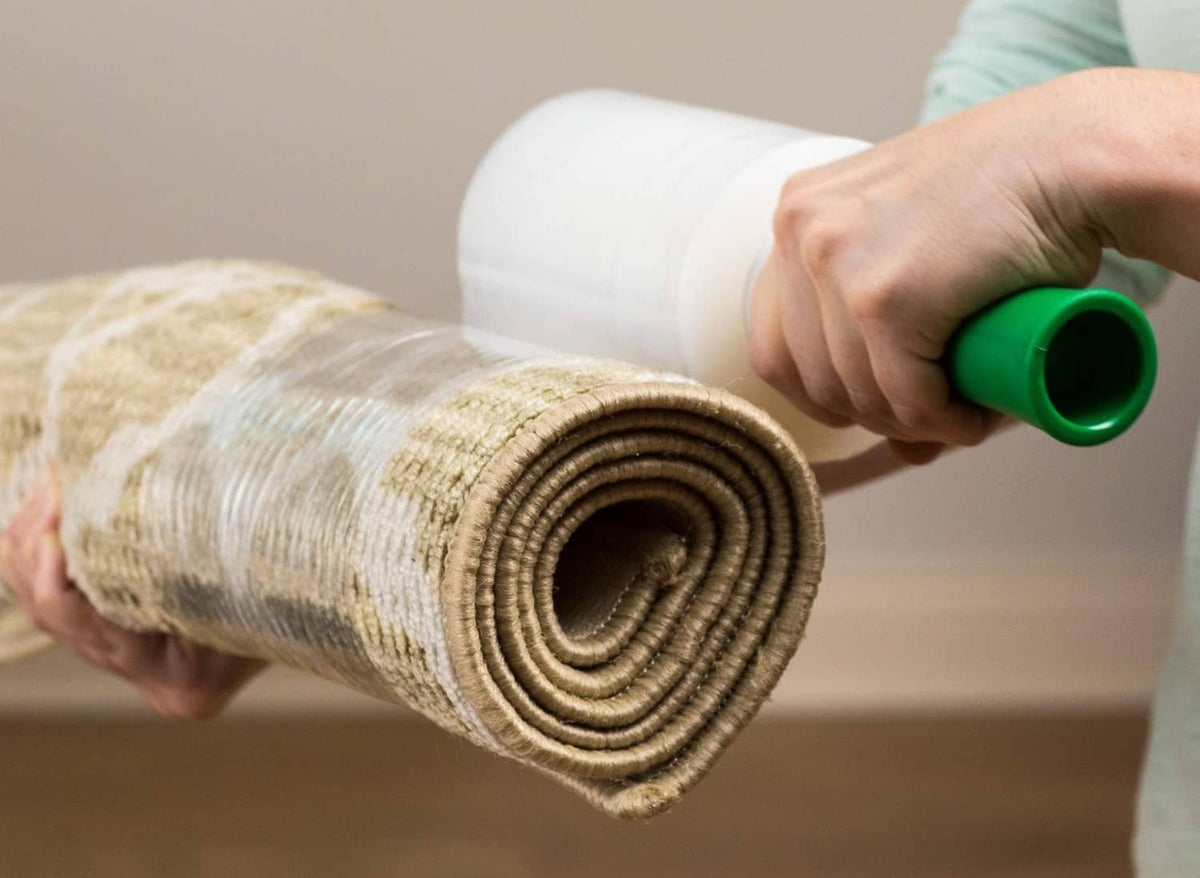 Person wrapping a bundled roll with Duck Brand stretch wrap; green dispenser in hand