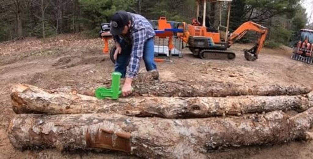 Firewood marking tool in green used on stacked logs by a person outdoors.