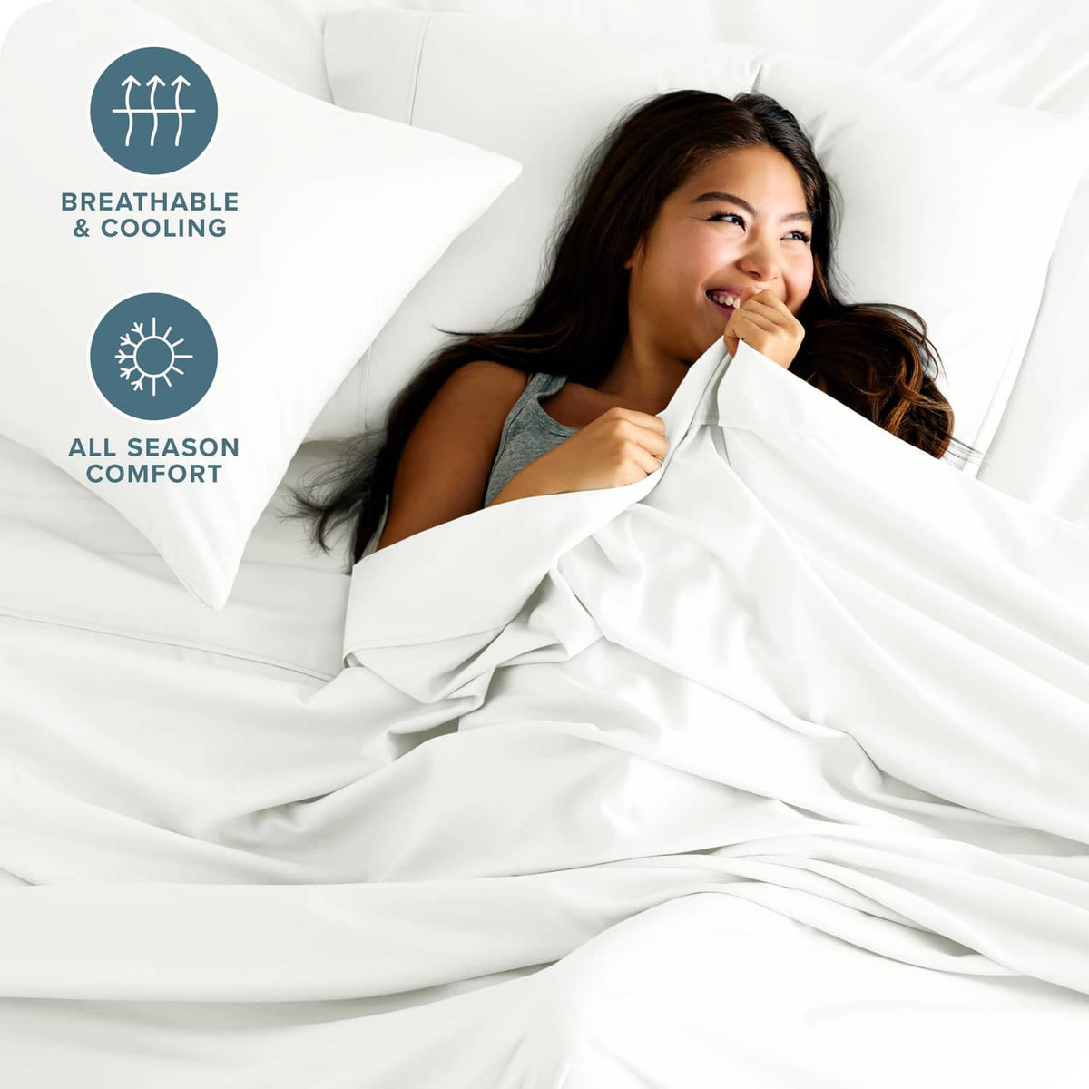 Cream bed sheet set on white pillows with a person relaxing under sheets
