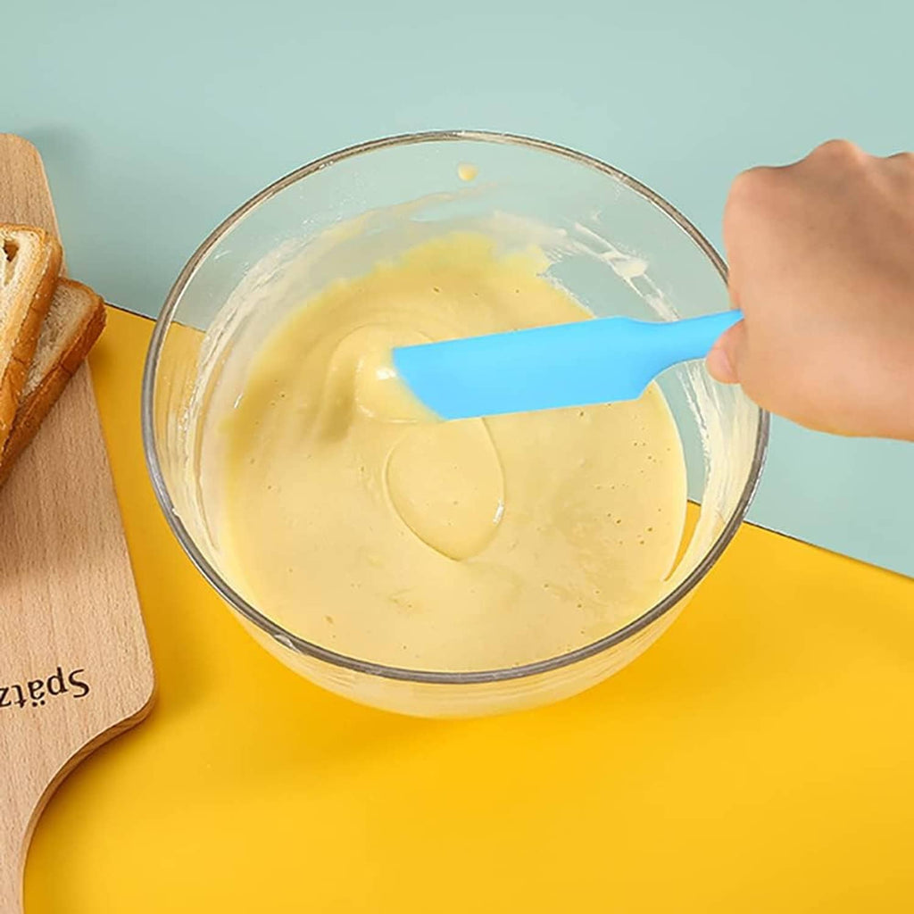 Blue silicone spatula stirring batter in a bowl, flexible flat edge