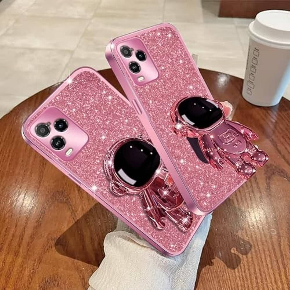 Rose gold glitter phone cases with astronaut kickstands on wood tabletop