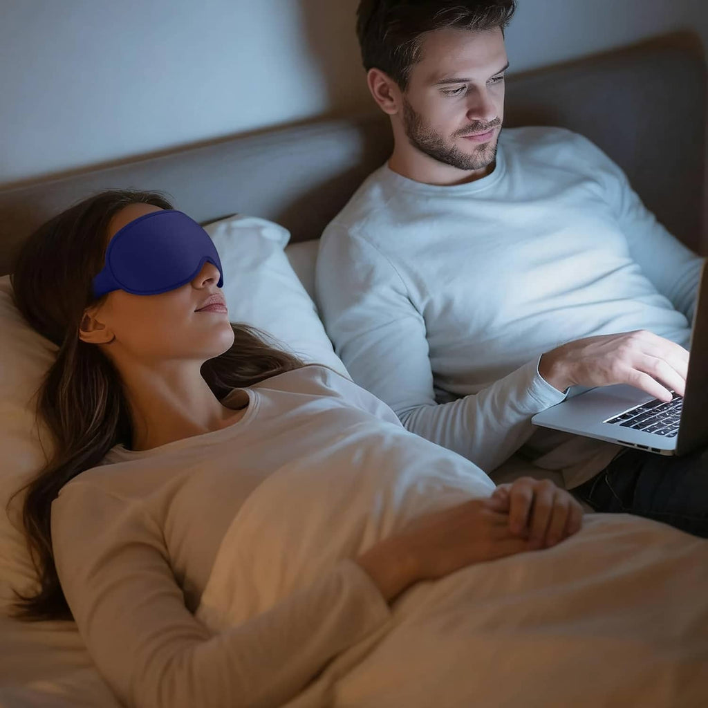 Blue sleep mask on a couple relaxing in bed while using a laptop