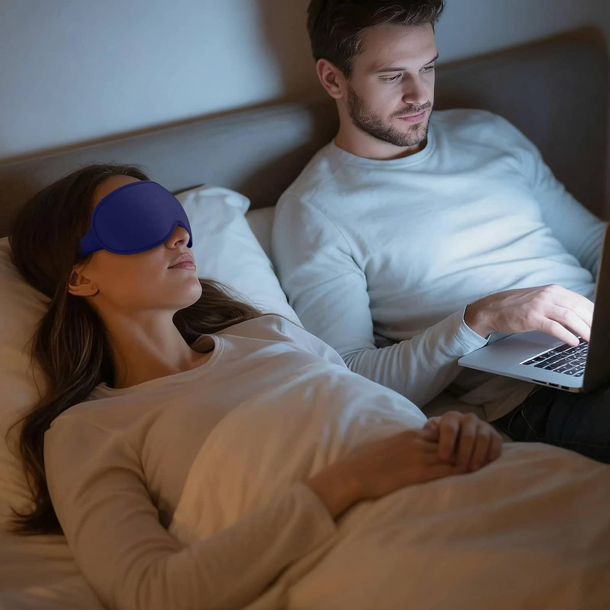 Blue sleep mask on a couple relaxing in bed while using a laptop