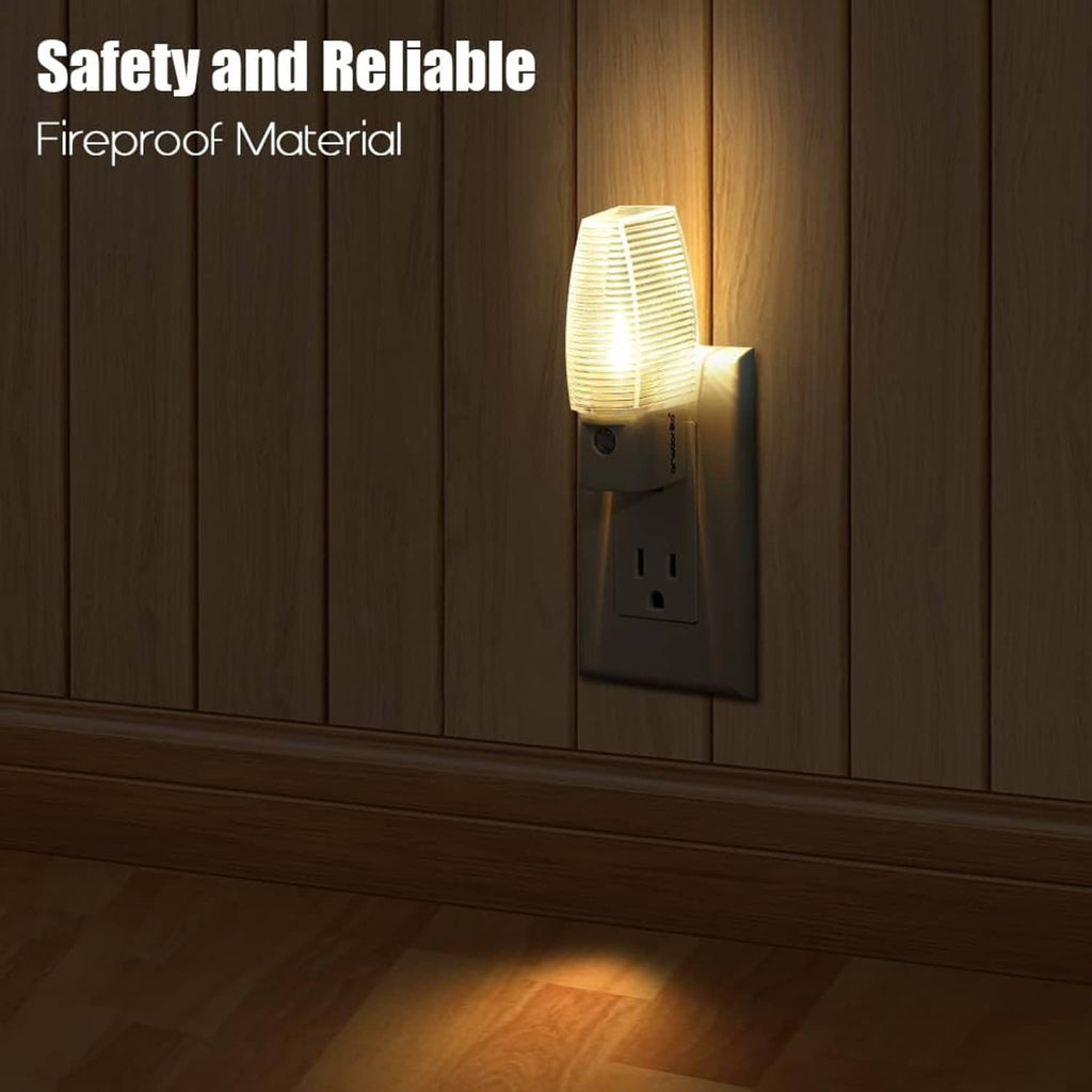 Plug-in LED night light mounted in wall outlet, emitting warm white light