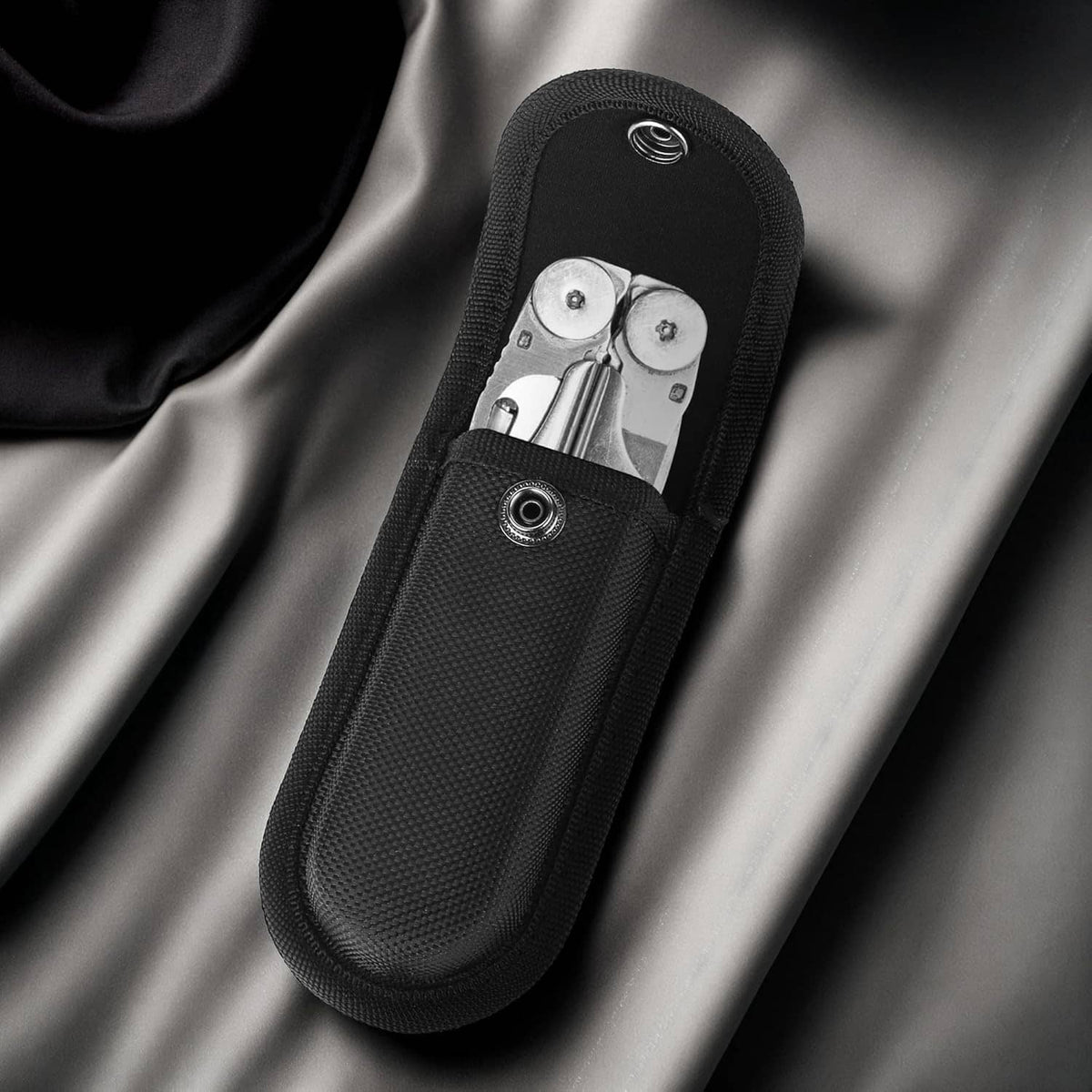 Black nylon knife sheath pouch with open top and snap hardware detail.