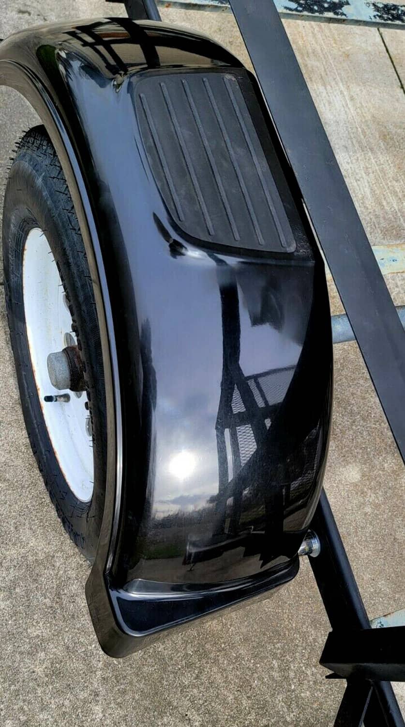 Black trailer fender with textured top panel mounted on a trailer wheel