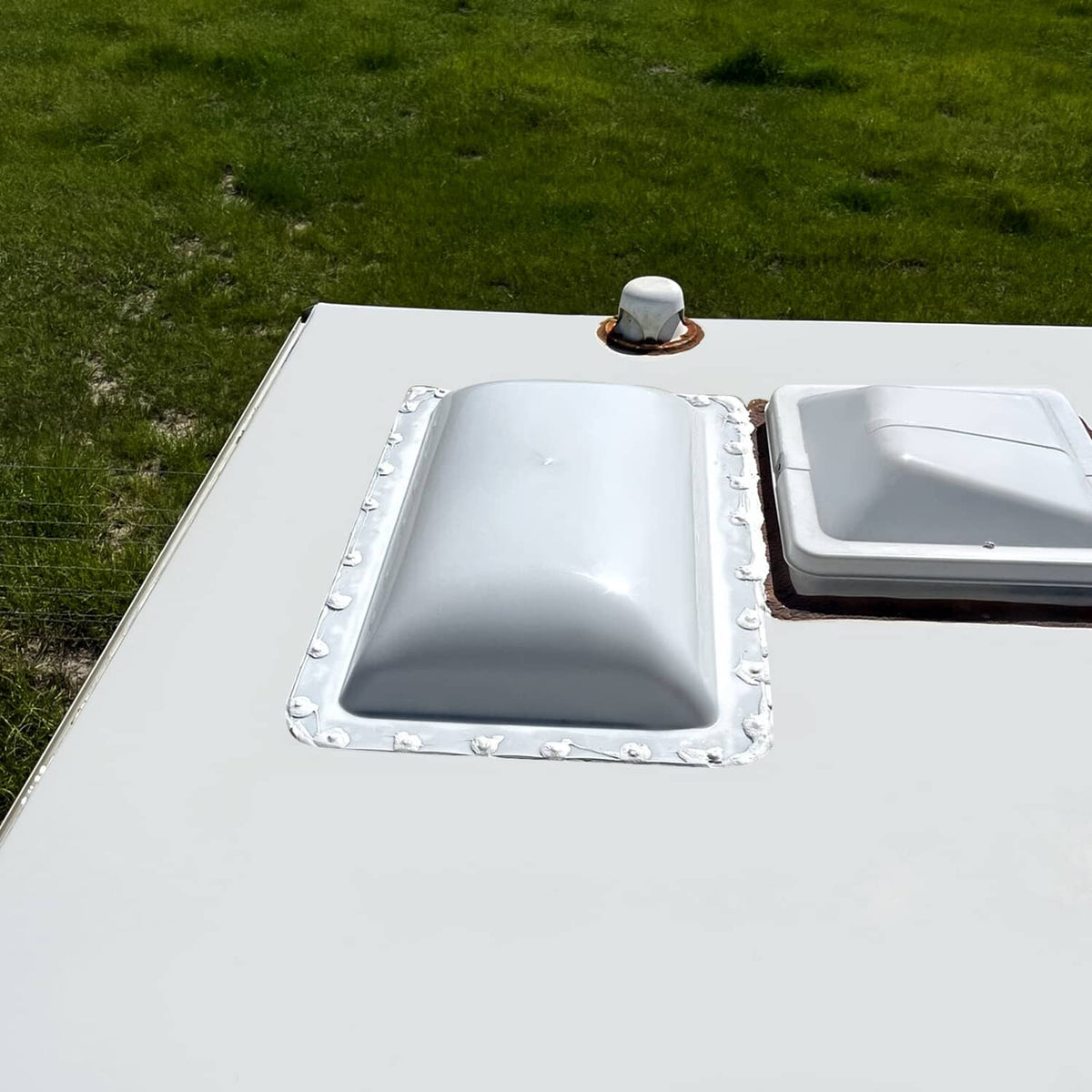 White camper skylight cover installed on roof opening with surrounding mounting border