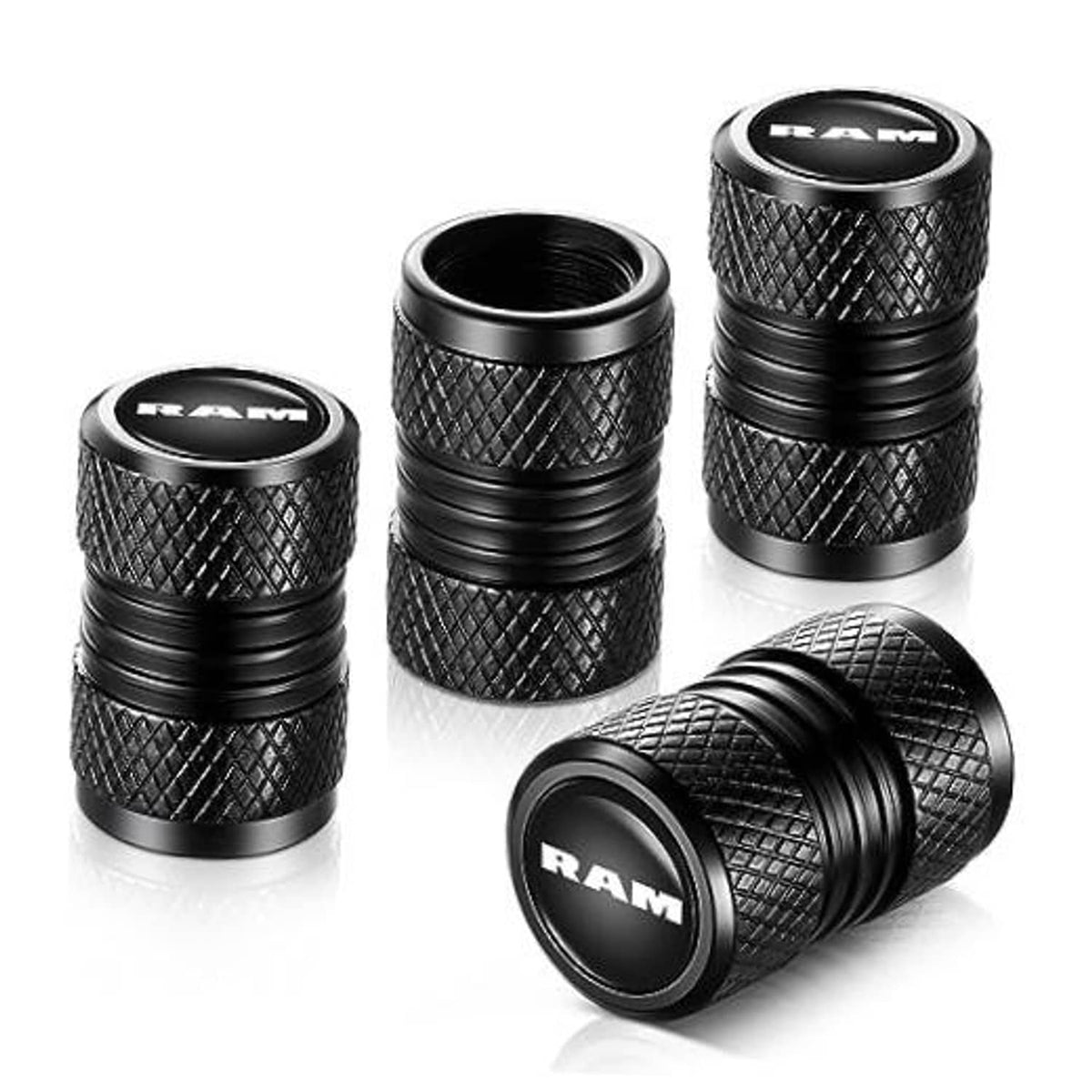 Four black RAM tire valve stem caps with knurled texture and ribbed sides