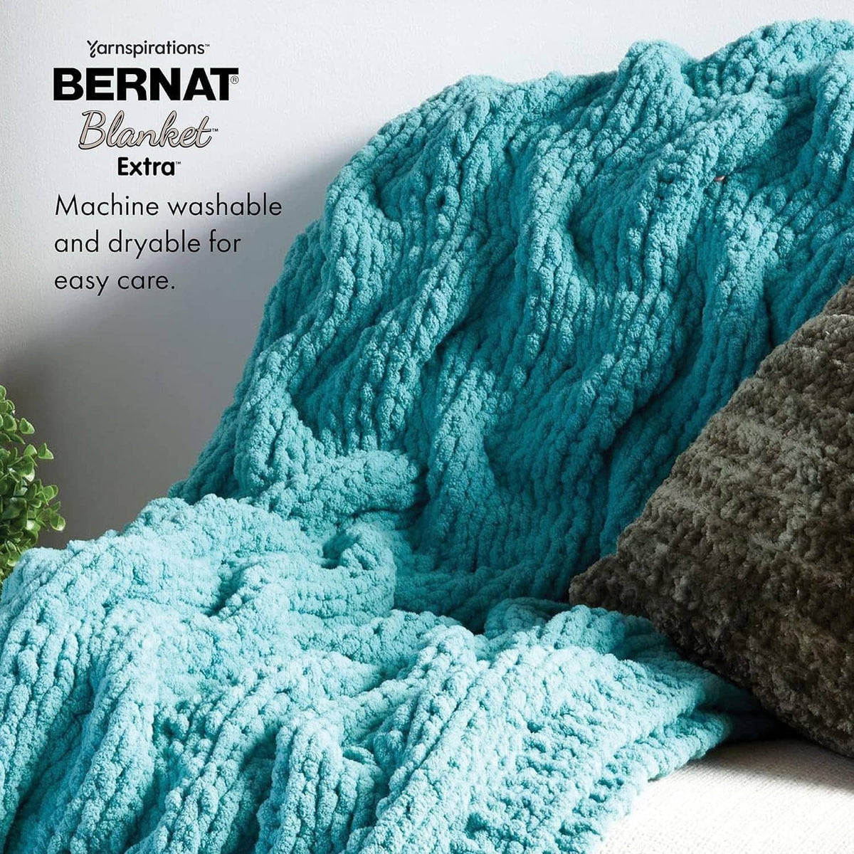 Teal chunky crochet blanket with ribbed chenille texture, draped over cushions