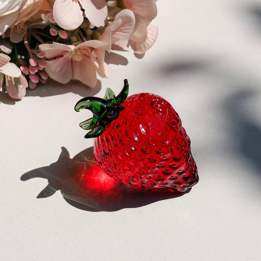 Red glass strawberry paperweight figurine with green leaves, glossy surface