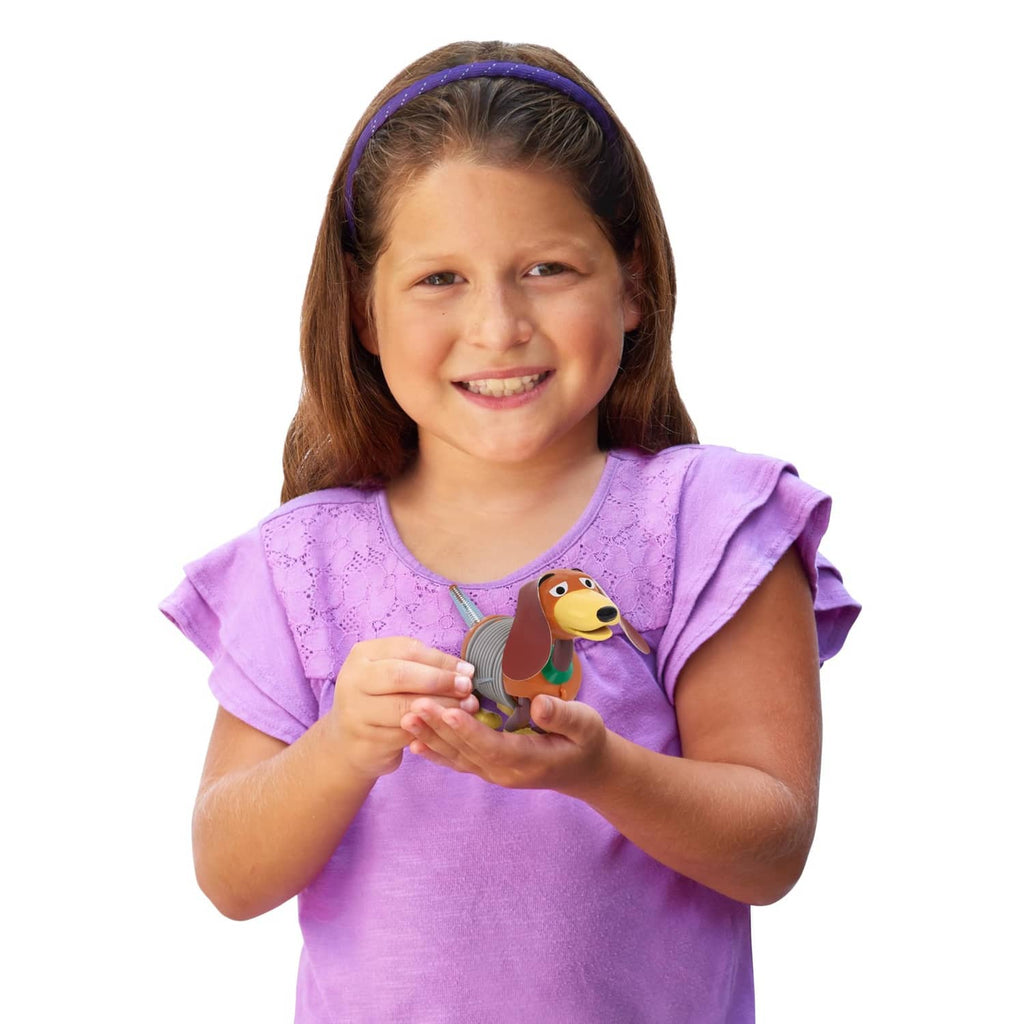 Slinky Dog wind-up toy held by a child, orange dog figure with gray coil spring