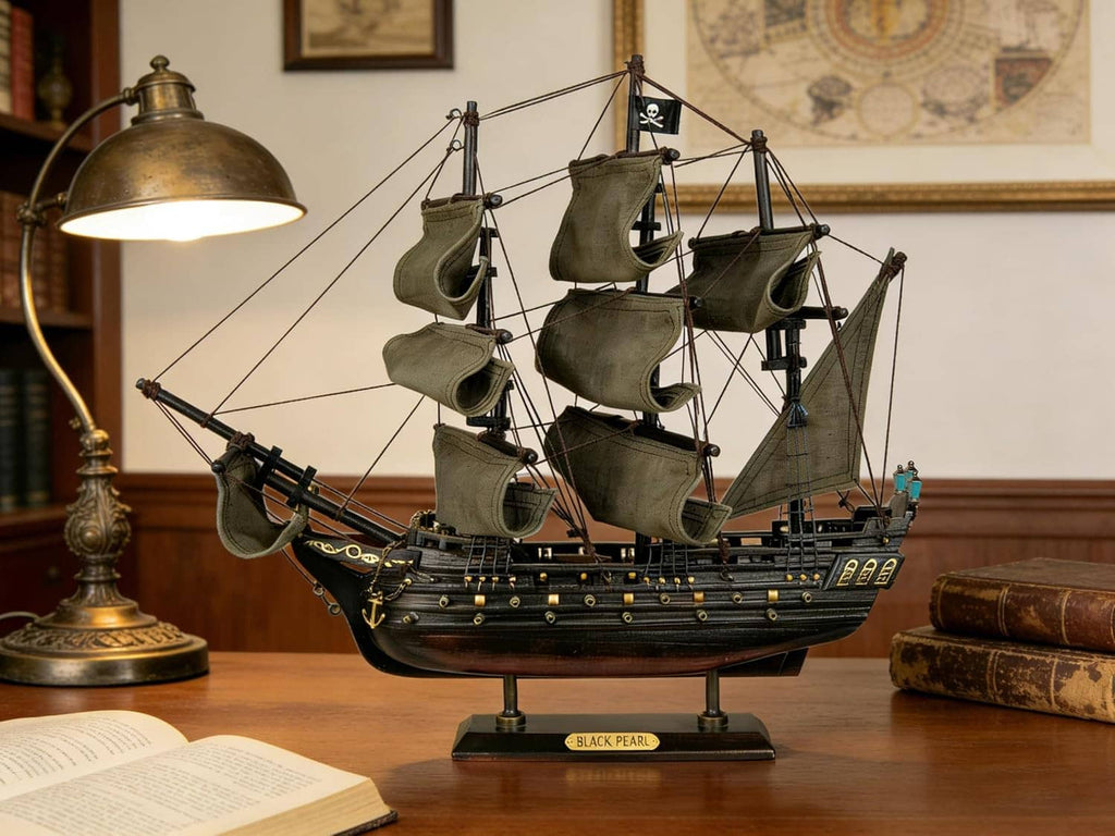 Wooden pirate ship model on desk with olive sails, “Black Pearl” nameplate, and lamp light