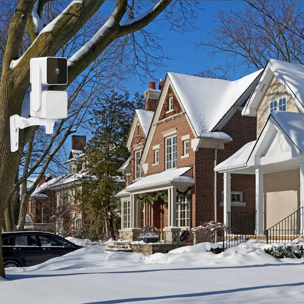 White outdoor wall camera mount installed on exterior house wall in snow