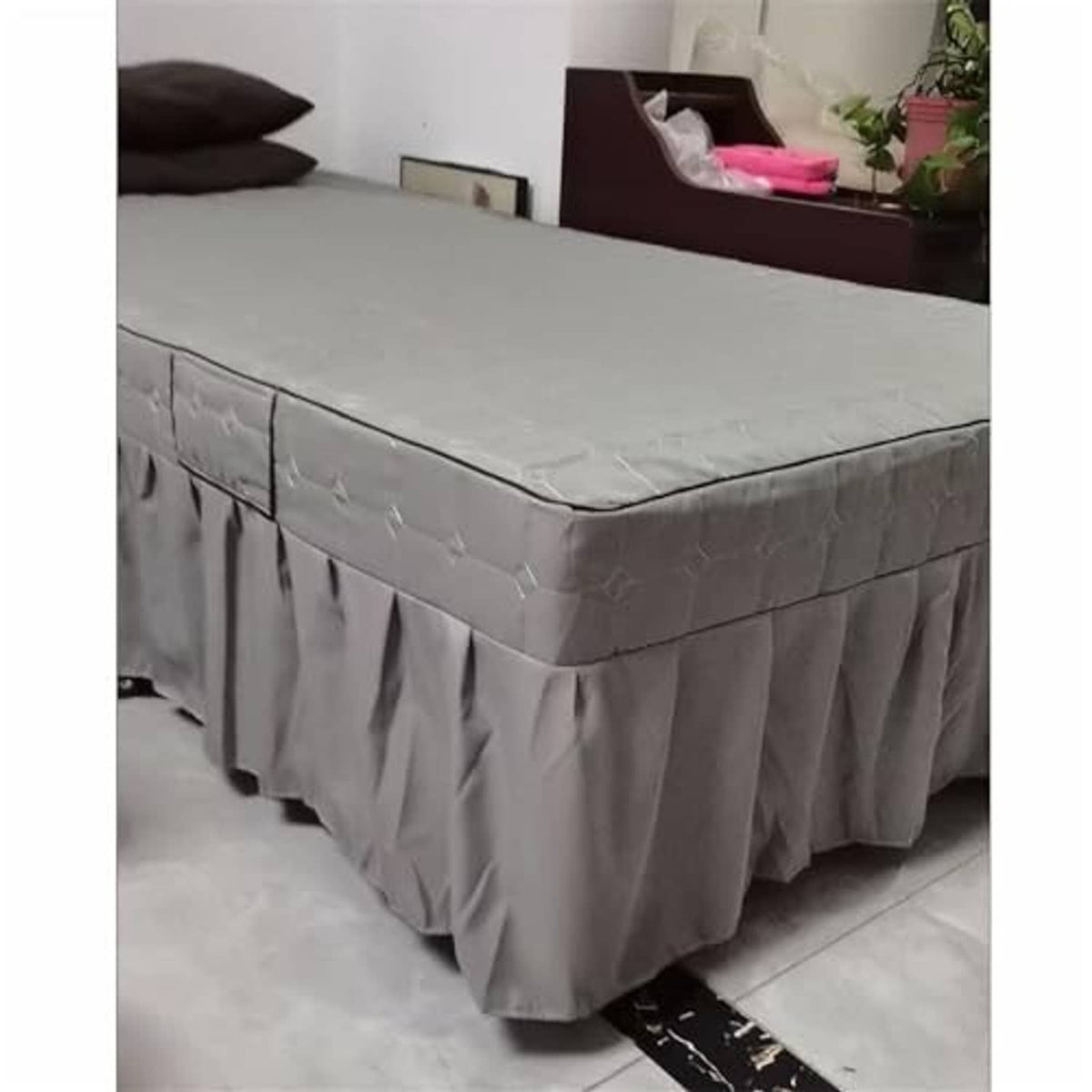 Grey quilted massage table skirt with long pleated drop, neatly fitted over corners