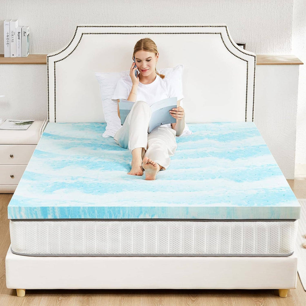 Blue mattress topper fitted on a bed over a mattress top