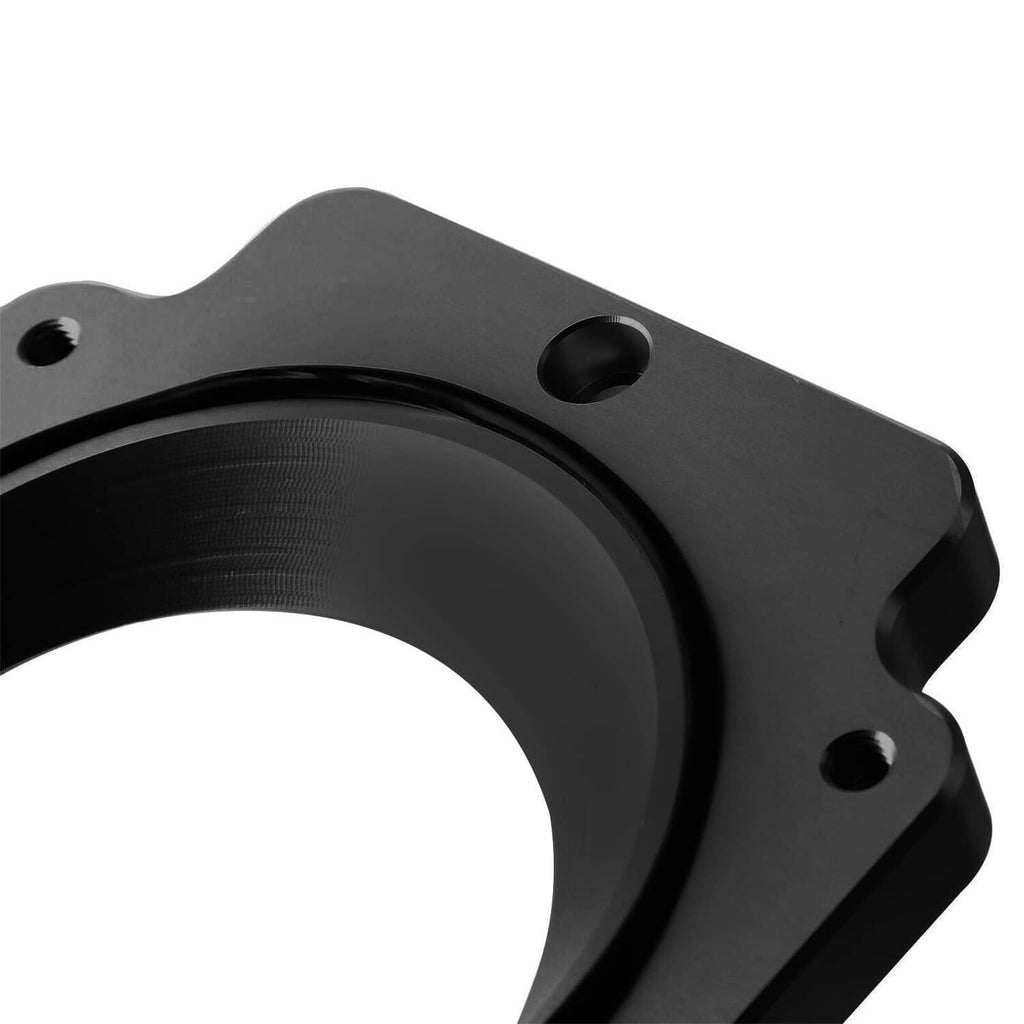 Black intake spacer adapter plate close-up with threaded mounting holes and round opening
