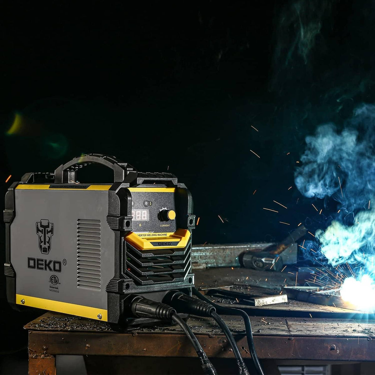 Gray and yellow MMA inverter welder producing blue arc sparks on metal plate