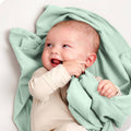 Mint green cotton flannel baby blanket wrapped around a newborn in close-up