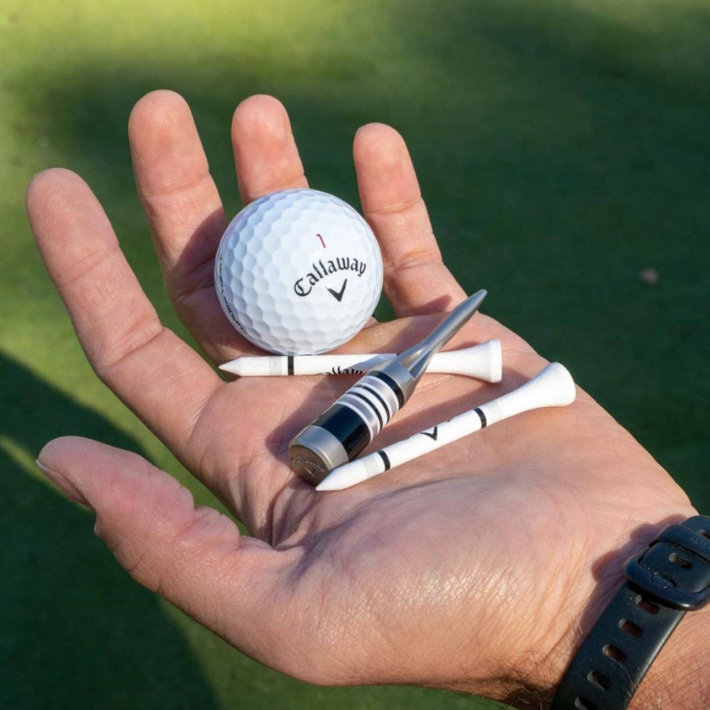 Silver divot tool held in a hand with a white Callaway golf ball