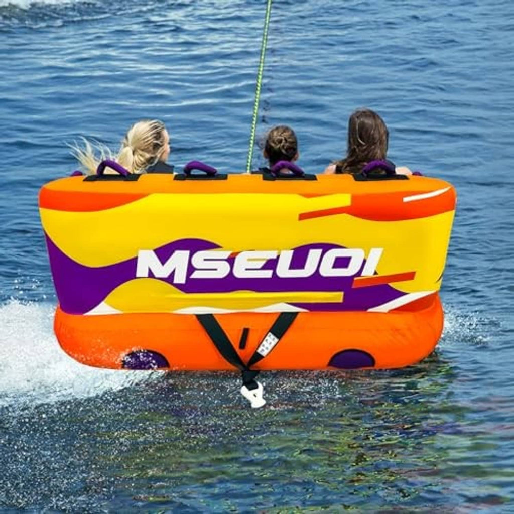 Orange and purple inflatable towable tube floating on water with riders seated inside.