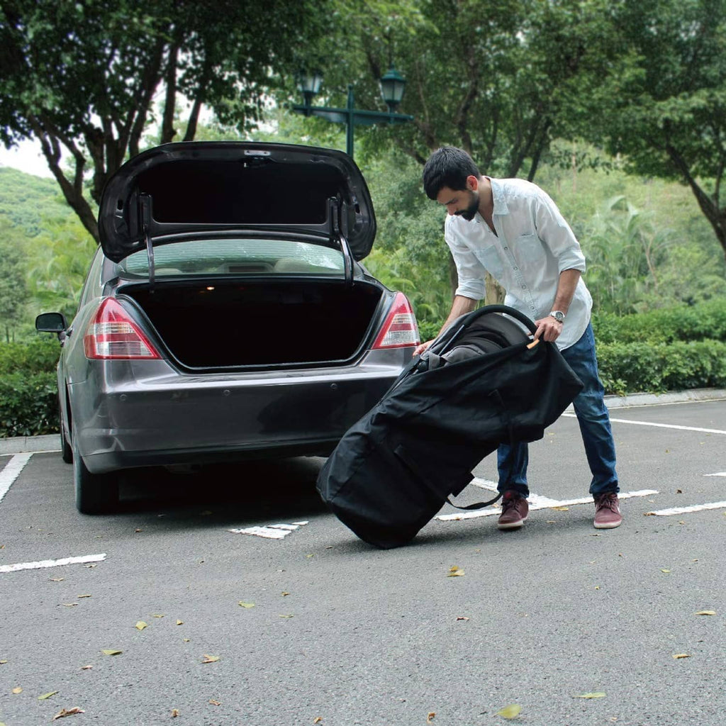 Black long duffel travel bag with top handles, open zipper, being loaded from a car trunk