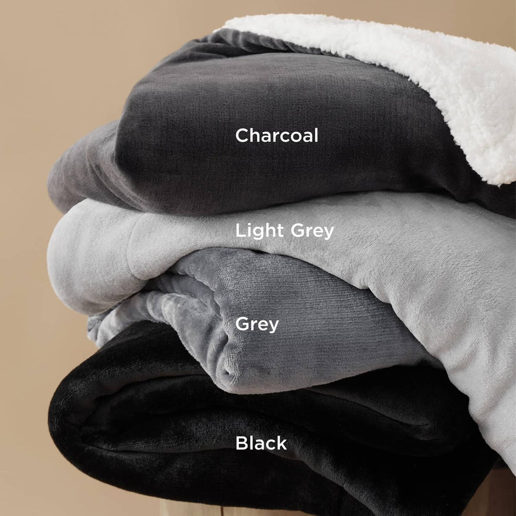 Stacked sherpa fleece throw blankets in charcoal, light grey, grey, and black