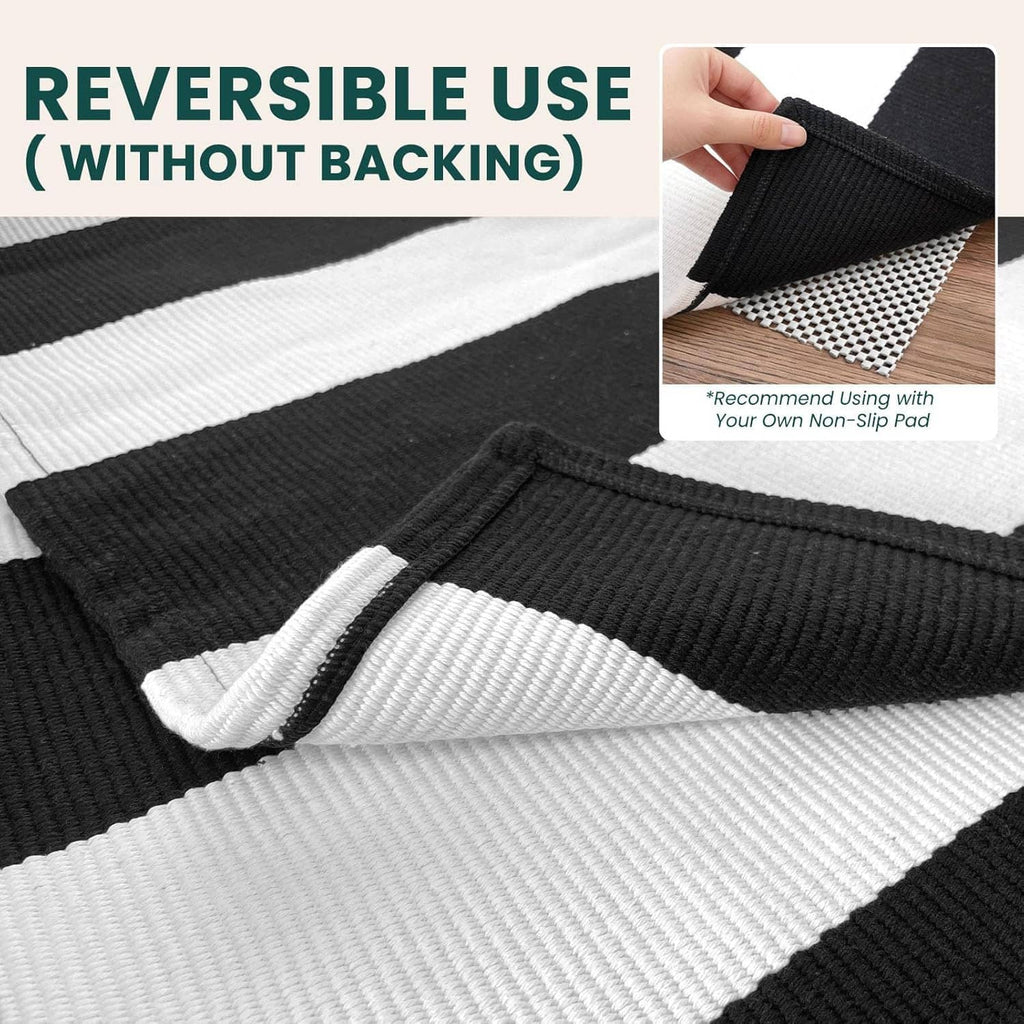 Reversible black-and-white striped area rug with textured weave and folded corner.