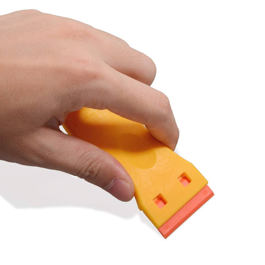 Close-up hand holding yellow plastic razor scraper tool with orange blade base