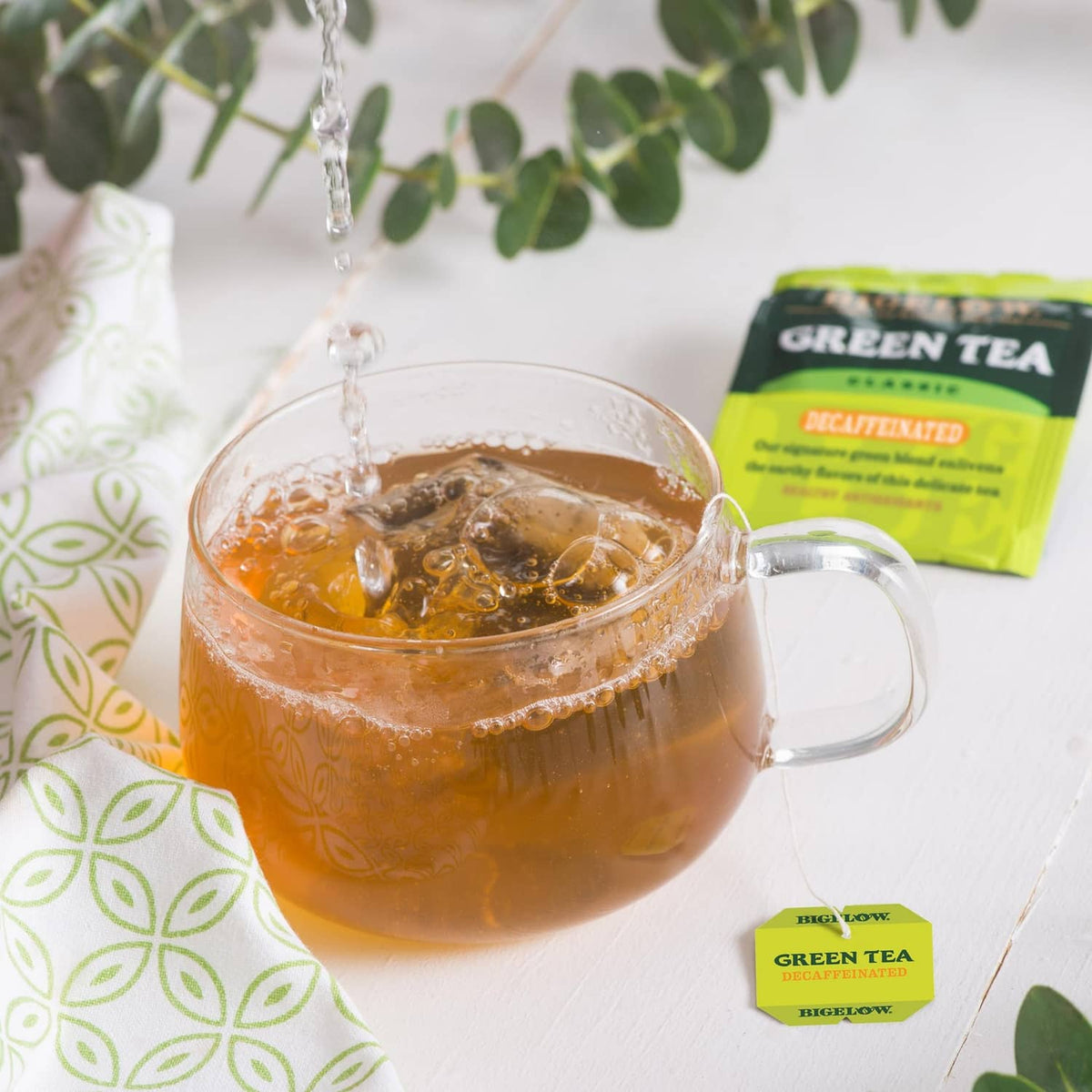 Glass mug of brewed decaf green tea with hanging tea bag and tea box