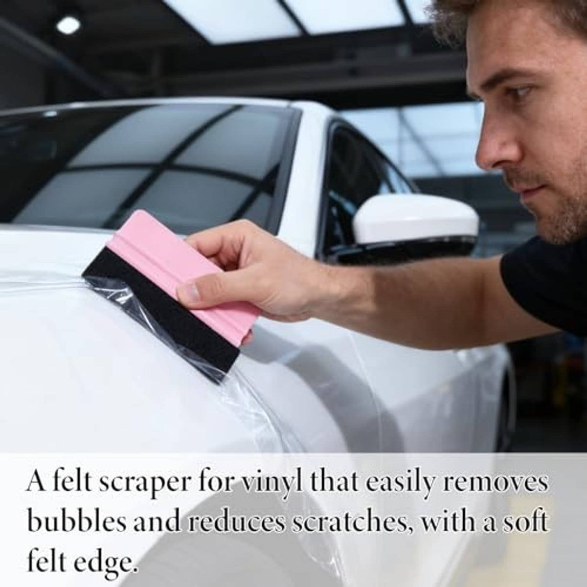 Pink felt squeegee used to smooth vinyl film on a car window