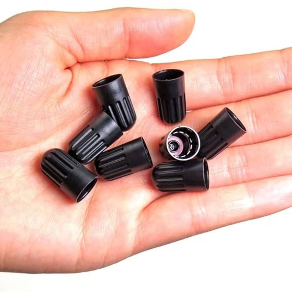 Black ribbed long tire valve stem caps in hand, open interiors visible