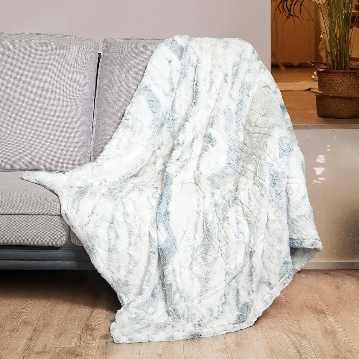 Light blue and white faux fur heated throw blanket, draped over seating