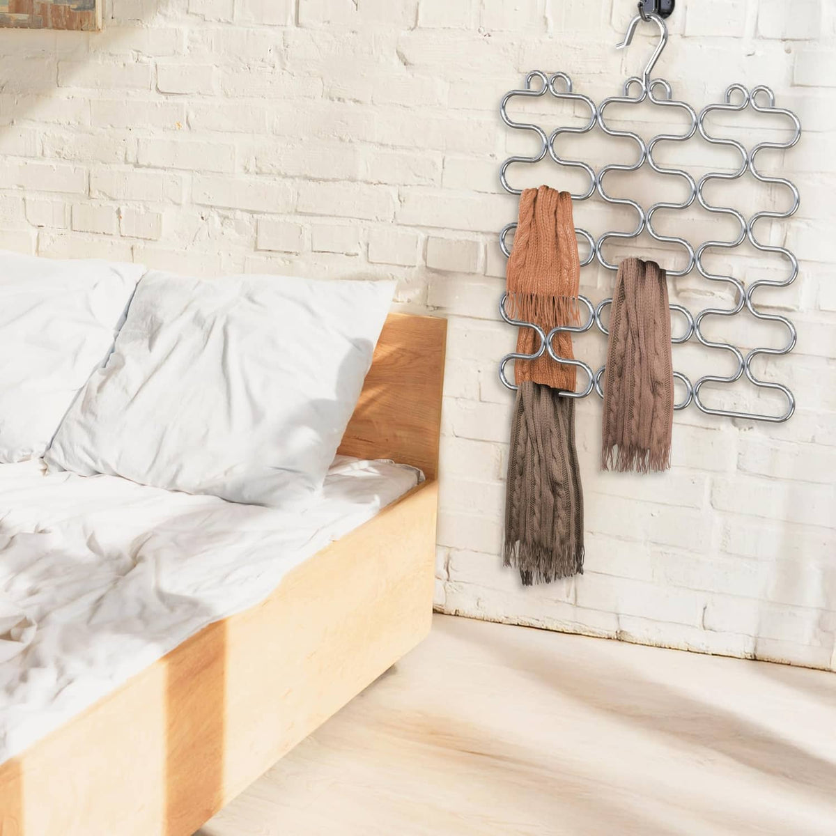 Chrome scarf hangers holding tan and brown scarves on a wall
