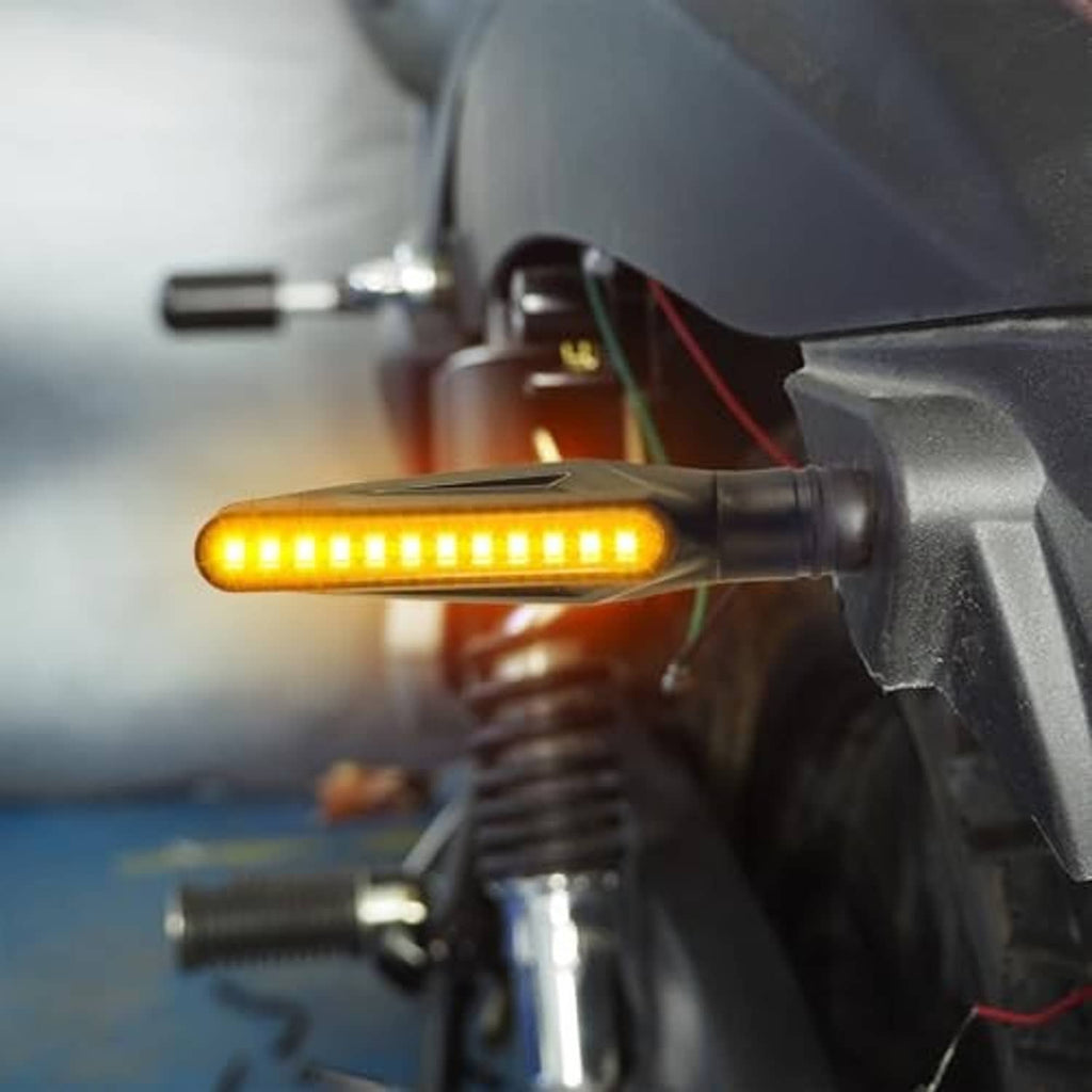 Close-up amber LED turn signal on motorcycle with black housing and threaded base