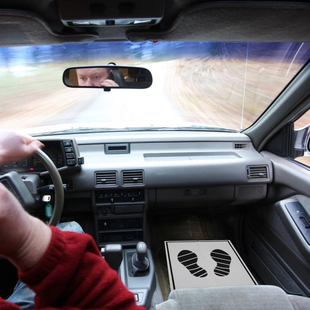 Disposable paper foot mat with black footprint print on front seat floor area