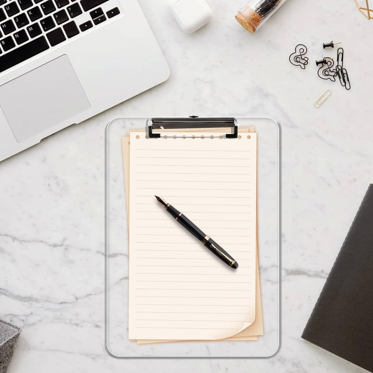 Transparent clipboard with metal clip holding a lined notepad sheet