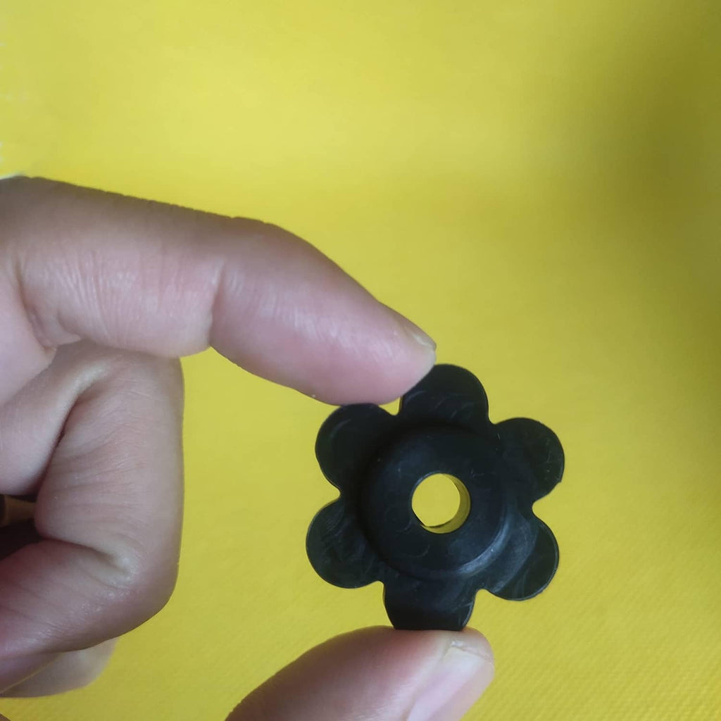 Black flower-shaped rubber garden flag stopper held in hand, showing center hole