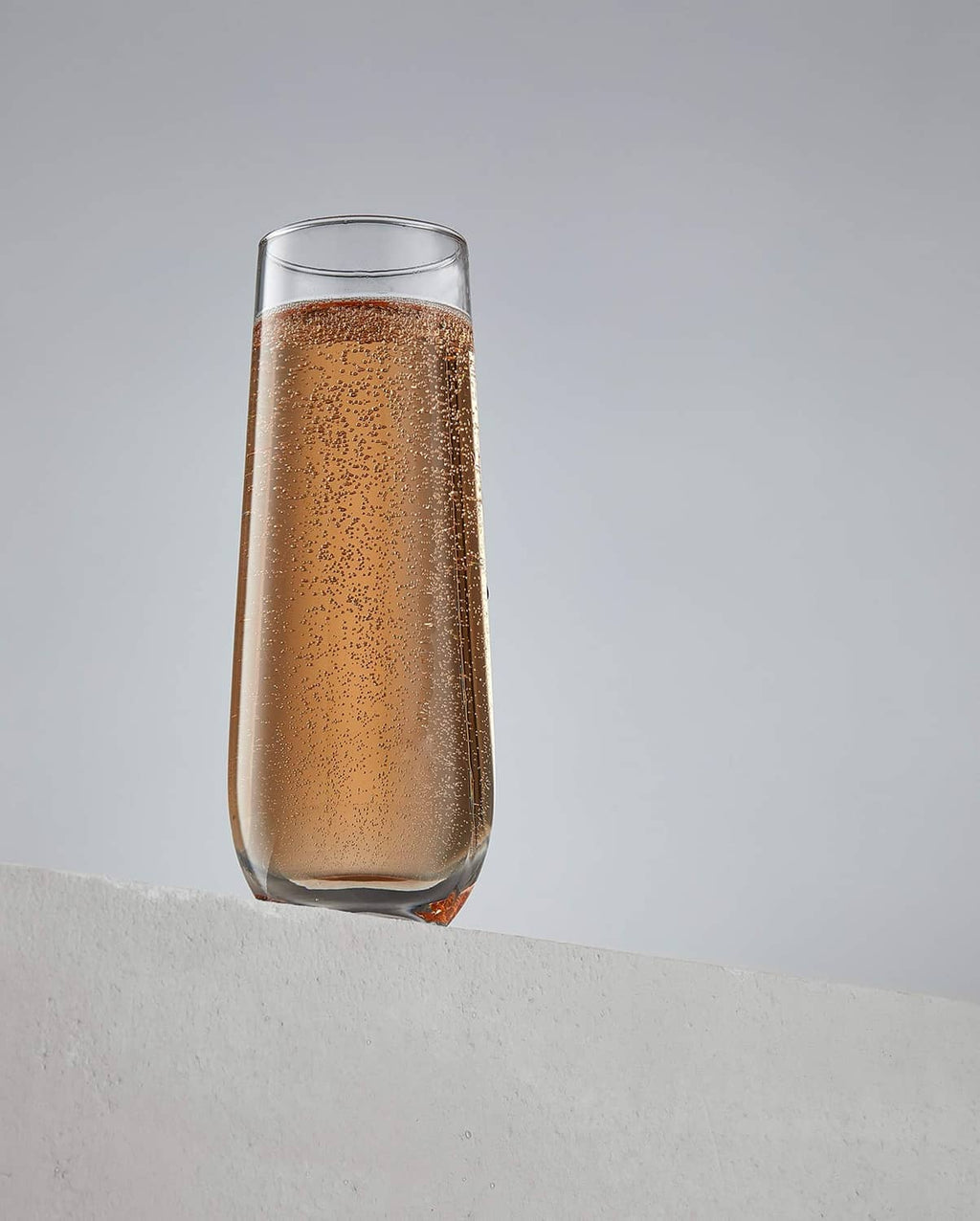Stemless champagne flute filled with golden sparkling drink, angled view