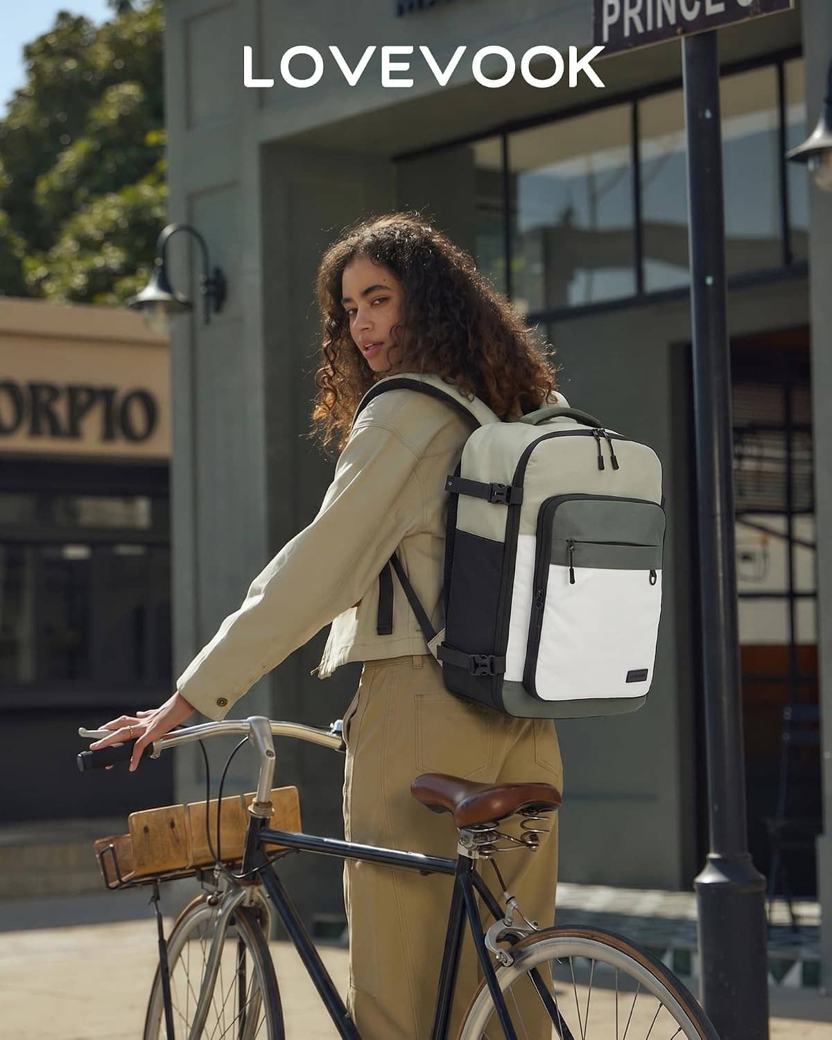 Olive and cream travel backpack worn while posing with a bicycle nearby