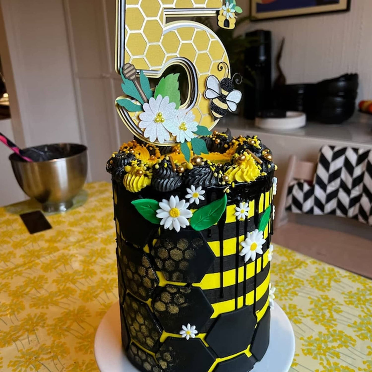 Bee-themed decorated cake with honeycomb and bee stencil details on black frosting