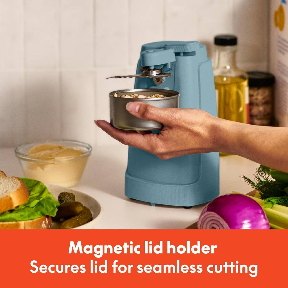 Teal electric can opener holding a can with a magnetic lid area for hands-free cutting