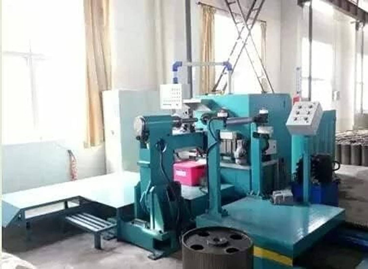 Teal industrial band saw machine with controls in workshop