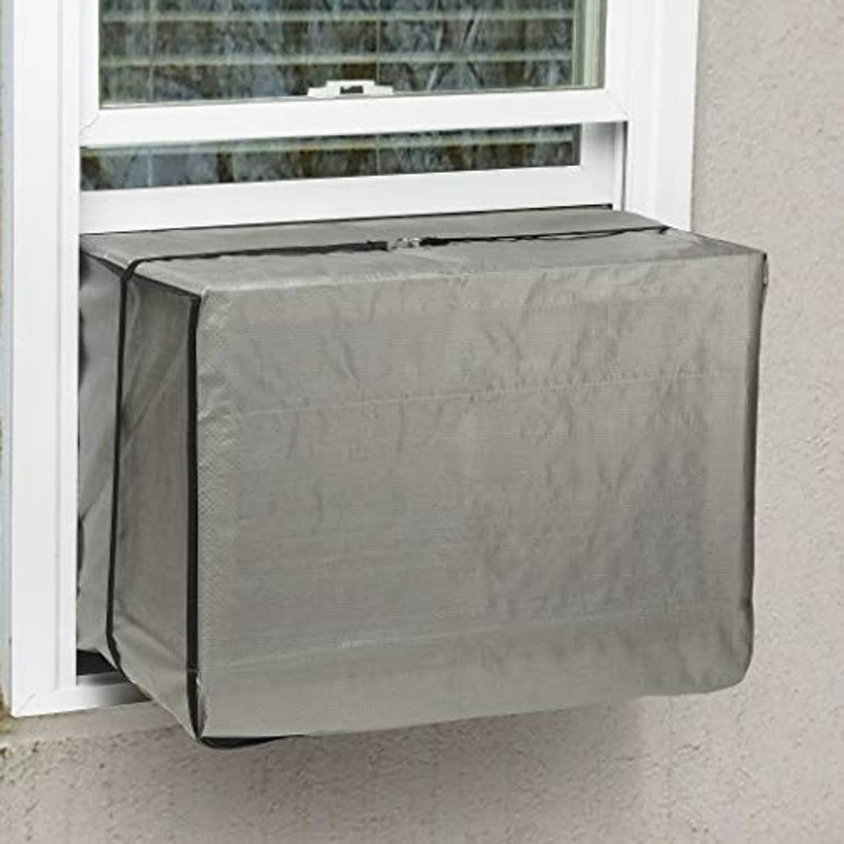 Gray window air conditioner cover fitted over outdoor AC unit in a window opening