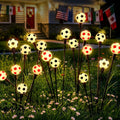 Solar soccer light set with glowing soccer-ball bulbs on black stakes in outdoor grass